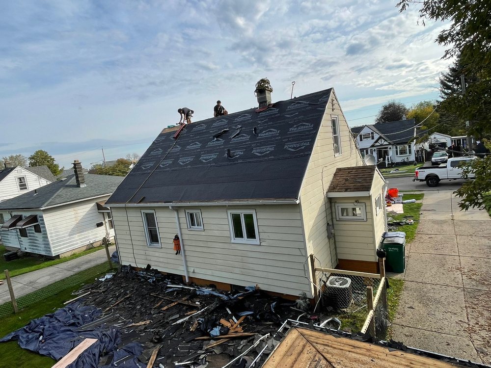 A roofing crew replacing shingles on a residential roof