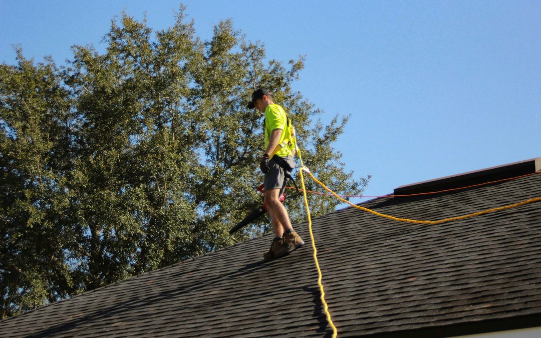 Roofing worker installing solar equipment on a rooftop while secured with a safety rope